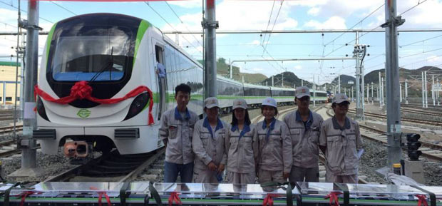 people posing for the camera in front of a white and green train